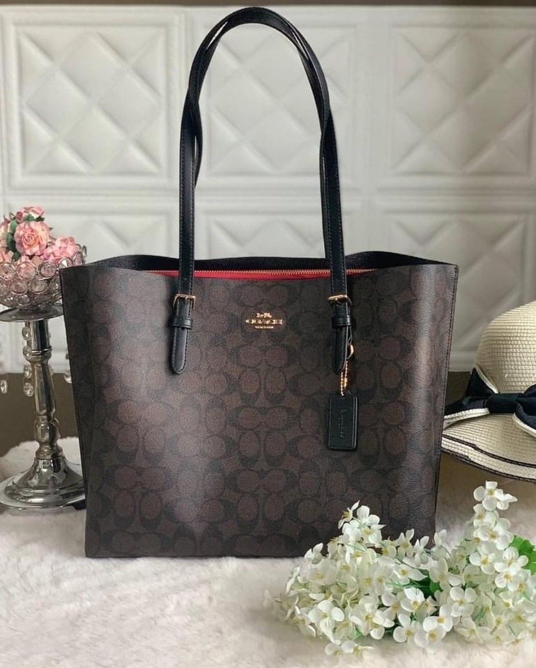 Brown patterned handbag with black handle on a light background
