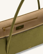 Green handbag with beige interior and gold zipper on a white background